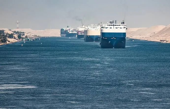 Cargo vessels navigating the Suez Canal in convoy.